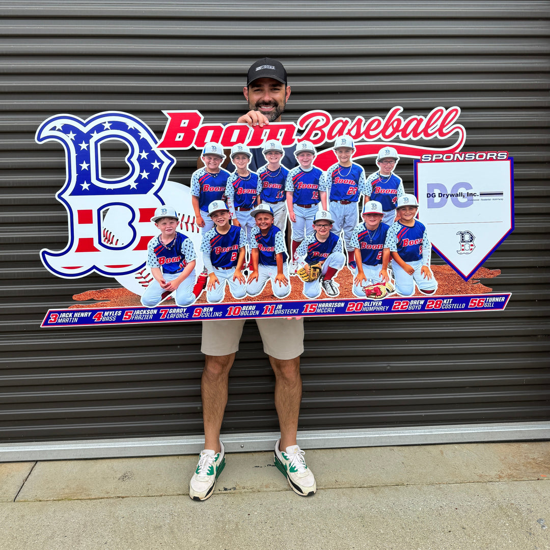 Person holding a large cutout of a baseball team with a branded backdrop.